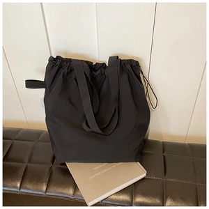 Detailed view of black nylon drawstring bucket bag on a black checkered bench