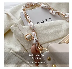 Detail of adjustable golden buckle and silk chain strap on beige bucket bag