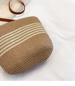 Macro detail of the woven straw bucket bag showing textured stripes and brown leather strap