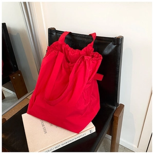 Detail of red nylon bucket bag with drawstring closure on a black leather chair