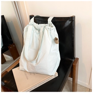 Detail of mint green nylon bucket bag featuring drawstring closure on a black leather chair