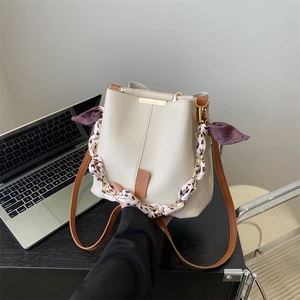 Chic beige bucket bag with leopard print chain handle and elegant purple bow accent