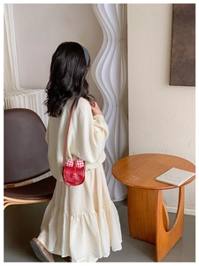 Détail d'un sac bandoulière rouge pour enfant avec un grand nœud à carreaux rouge et blanc
