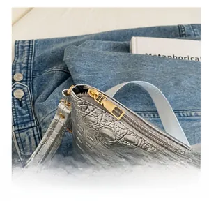 Close-up of smooth metal zipper and silver crocodile texture on large envelope clutch bag