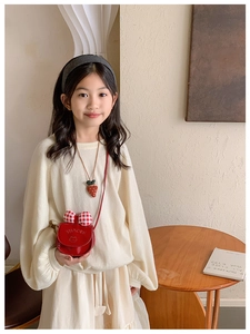 Détail du sac bandoulière en cuir verni rouge pour fille avec nœud et breloque fraise