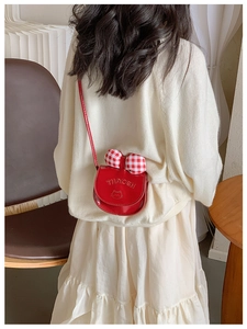 Détail du sac à bandoulière brillant rouge pour enfant avec nœud à carreaux et chat
