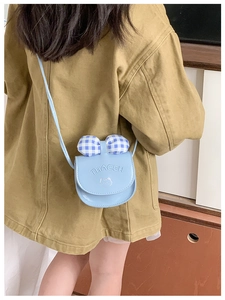 Fillette portant un petit sac bandoulière bleu avec nœud à carreaux et chat