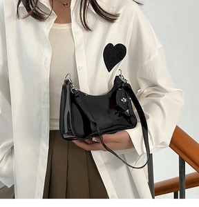 Detailed view of the shiny black patent leather underarm bag with a slim shoulder strap