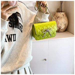 Detailopname van felgroene gewatteerde crossbodytas met een sprankelende strikgesp