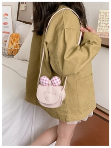 Vue détaillée d'un petit sac bandoulière rose avec nœud à carreaux porté par une enfant