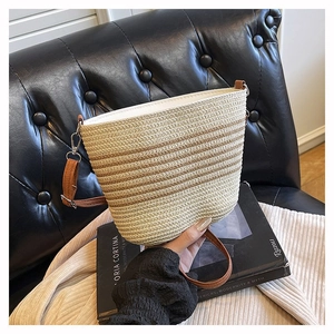 Close-up of the woven texture and leather strap on this striped straw bucket bag