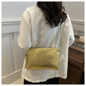 Detail of gold crocodile embossed envelope bag with adjustable shoulder strap for women