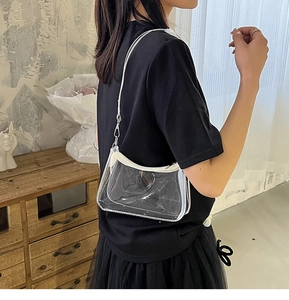 Close-up of clear PVC underarm bag with white trim and delicate silver chain strap