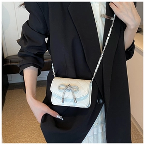 Detail van witte gewatteerde crossbodytas met zilveren strass-strik en een kettingriem