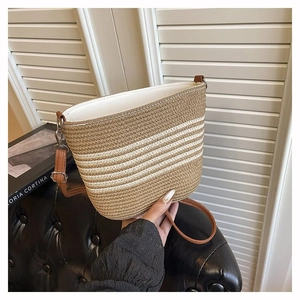 Macro detail of the woven straw texture and striped bucket bag with adjustable strap