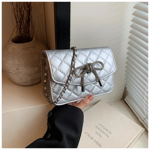 Detail van de zilveren gewatteerde crossbodytas met strass-strik en kettingriem