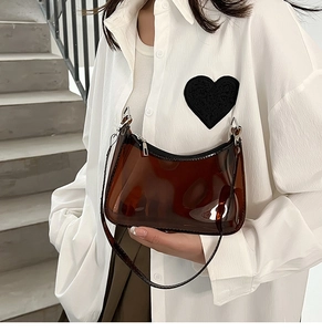 Detail of a brown transparent PVC crescent bag with silver zipper and sleek shoulder strap
