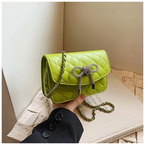 Detail van groene gewatteerde tas met fonkelende strik en ketting schouderriem