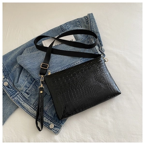 Detail of black crocodile texture bag with golden zipper and wide nylon strap
