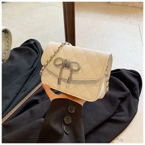 Detail van witte gewatteerde crossbodytas met strass-strik en lederen kettingriem