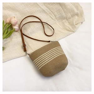 Detail of hand-woven straw bucket bag with white stripes and adjustable leather strap