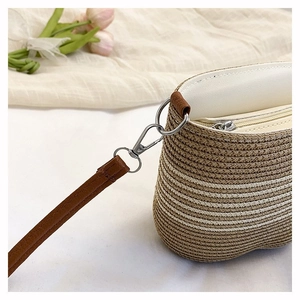 Detail of hand-woven striped bucket bag showing zipper closure and metal strap rings
