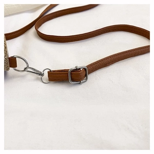 Detail of brown lychee leather shoulder strap with silver metal buckle and lobster clasp