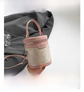 Détail d'un sac seau en cuir rose et jacquard beige avec poignée et fermeture éclair
