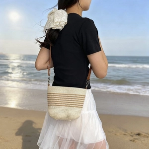 Detail of striped straw bucket bag worn by model on a sunny beach background
