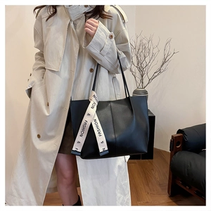Close-up of a large black leather tote bag with a decorative fashion silk scarf detail