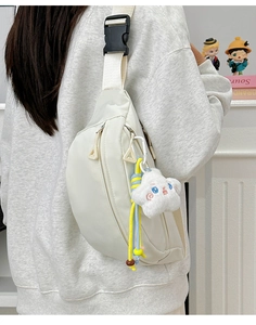 Detail of off-white nylon chest bag with dual zippers and plush star charm pendant