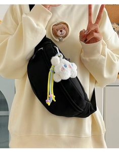 Detail of black nylon crescent chest bag with cute star plush keychain on model