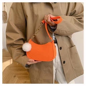 Orange moon-shaped crossbody bag with V-quilt pattern and white faux fur pompom charm