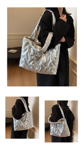 Detail view of large silver quilted tote bag showing metallic texture and wide shoulder strap