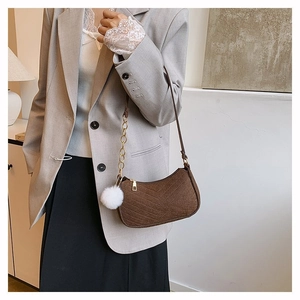 Detail of coffee-colored quilted felt hobo bag with V-shaped stitching and plush pompom