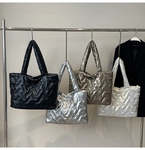 Quilted tote bags in black silver gold and white hanging on metal rack for display