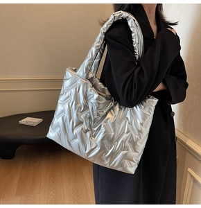 Detail of silver metallic quilted tote bag with wide strap and shiny puffer texture