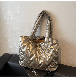 Detail of quilted champagne gold tote bag with metallic finish on black sofa