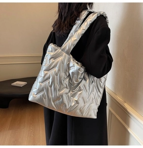 Detail of silver metallic quilted tote bag with V-shaped texture shown by model
