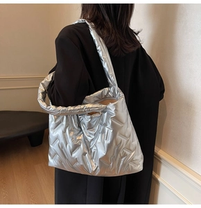 Detail of silver metallic quilted tote bag with padded texture and wide shoulder strap