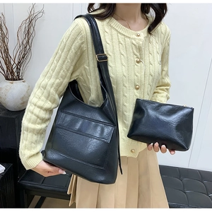 Detail of black glossy leather handbag set with adjustable strap and golden buckle