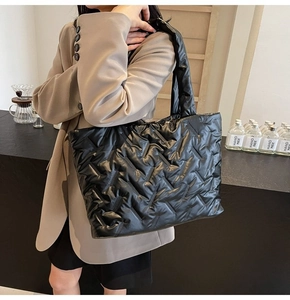 Close-up of black quilted down tote bag with high-gloss finish and thick shoulder strap