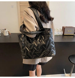 Lifestyle shot of large black quilted tote bag worn over the shoulder for commute