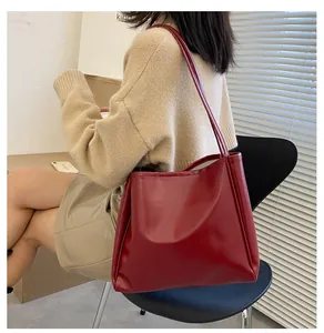 Detail view of burgundy tote bag with smooth texture and slim dual shoulder straps