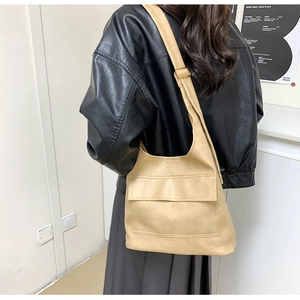 Detail view of large beige PU leather shoulder bag with gold buckles and wide strap