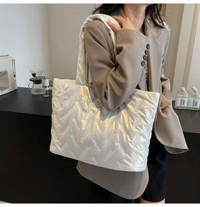 Detail of white quilted tote bag with metallic glossy finish and V-shaped stitching