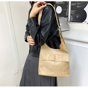 Detail of minimalist beige tote bag with front pocket flap and soft leather texture