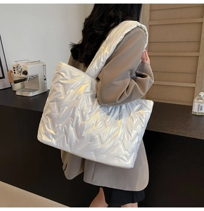 Detail of white quilted tote bag with V-shaped stitching and padded shoulder strap