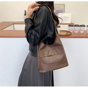Close-up of a brown vintage Hobo shoulder bag made of soft PU leather on a model