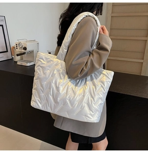 Close-up of white quilted tote bag featuring metallic luster and soft V-stitch details